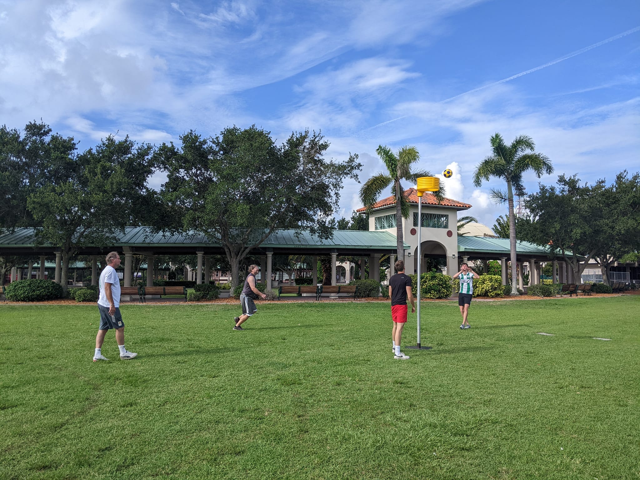 Korfball basket and players in a Florida park with palm trees